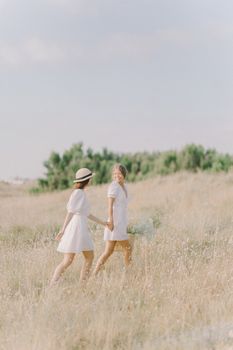 夏日，两个女人手牵着手，走过宁静的田野