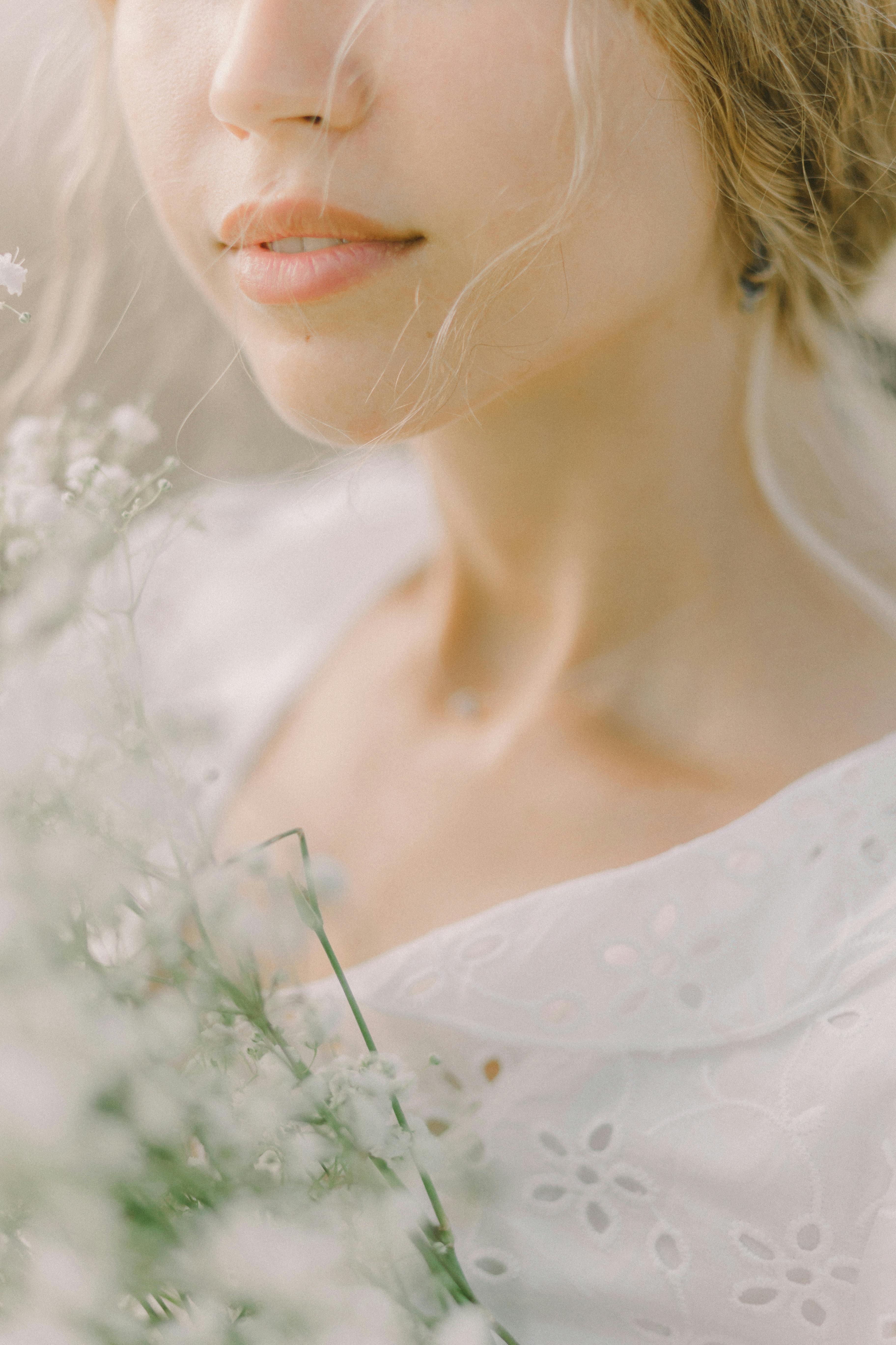 一名穿着白色蕾丝衬衫、开着白花的女人的特写