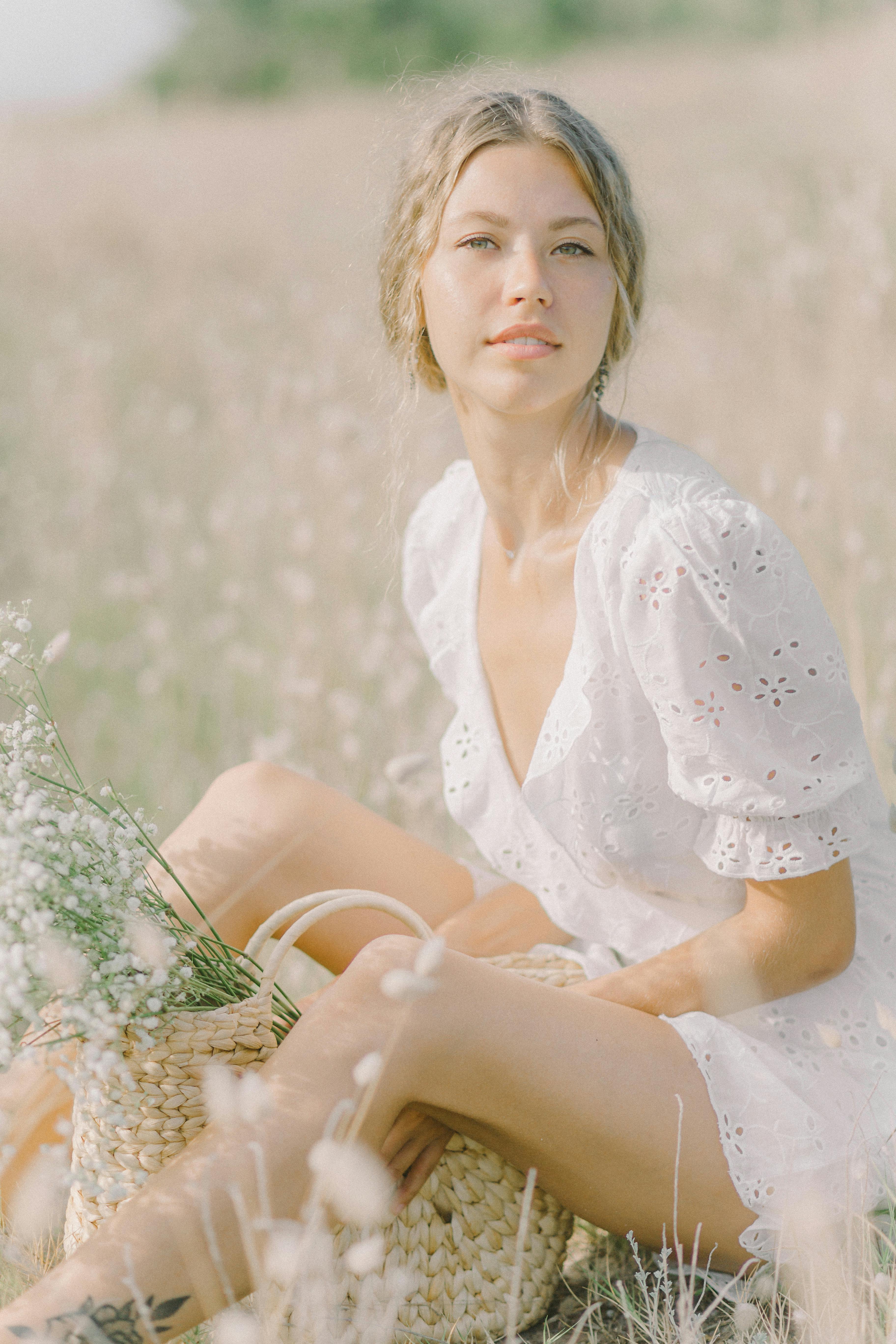 a woman in white dress sitting on flower field