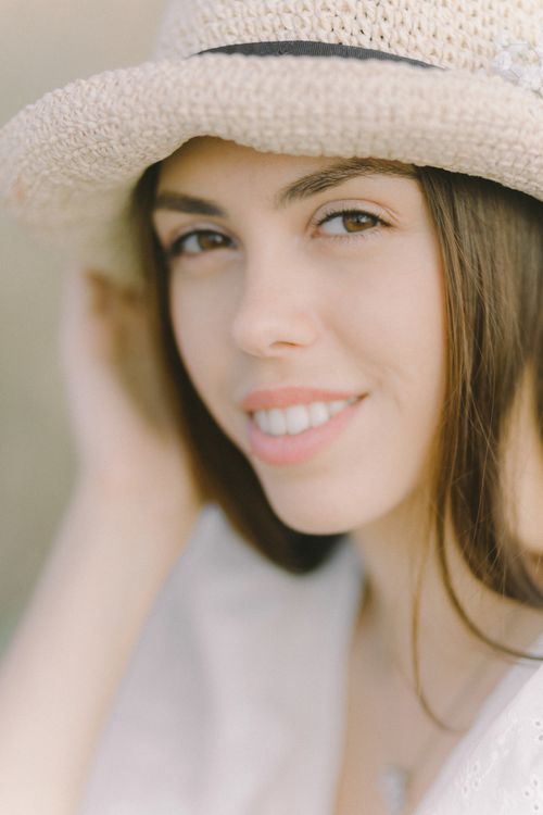 Free Close-up portrait of a smiling woman wearing a straw hat outdoors. Stock Photo