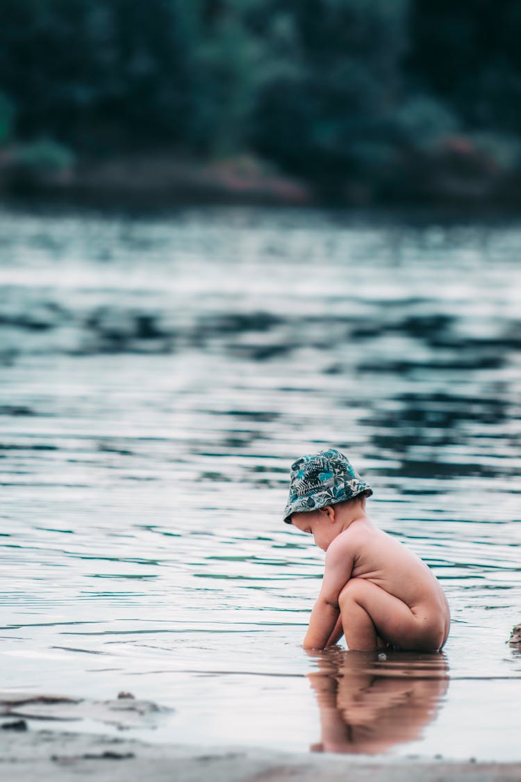 Cute Naked Little Child Sitting In River Water