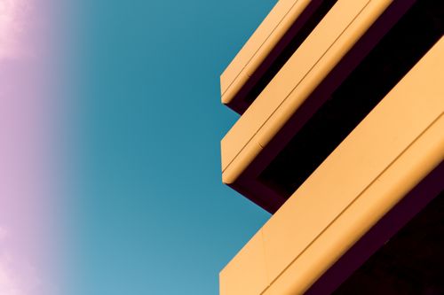 Free From below of exterior fragment of modern building with big terraces against cloudless blue sky on sunny day Stock Photo