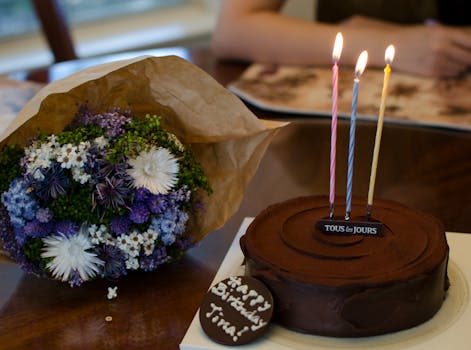 Celebrate with chocolate cake and floral bouquet, featuring lighted candles for a festive occasion.