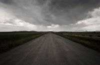 Gray Road Between Green Grass Under Gray Clouds