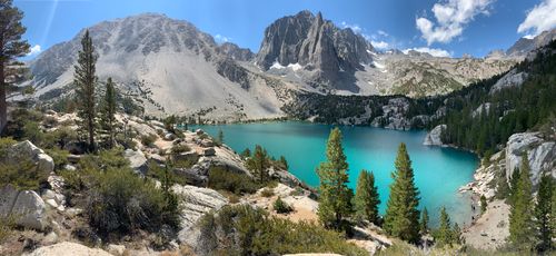 Free A breathtaking view of an alpine lake with turquoise waters set against a mountain backdrop. Stock Photo