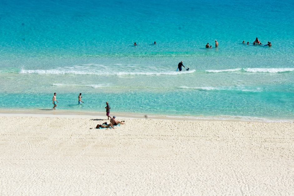 Sunbathers and swimmers enjoy a sunny day at a pristine white sand beach. - The Boatyard Barbados: Daytime Beach Club to Nighttime Party