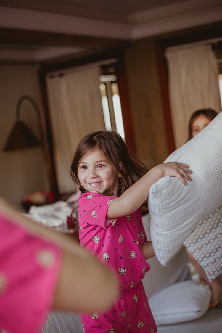 A Young Smiling And Holding A Pillow