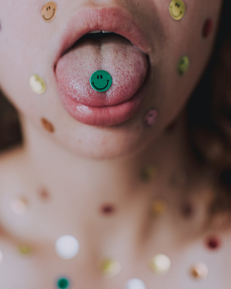 Woman With Multicolored Smiley Stickers On Tongue