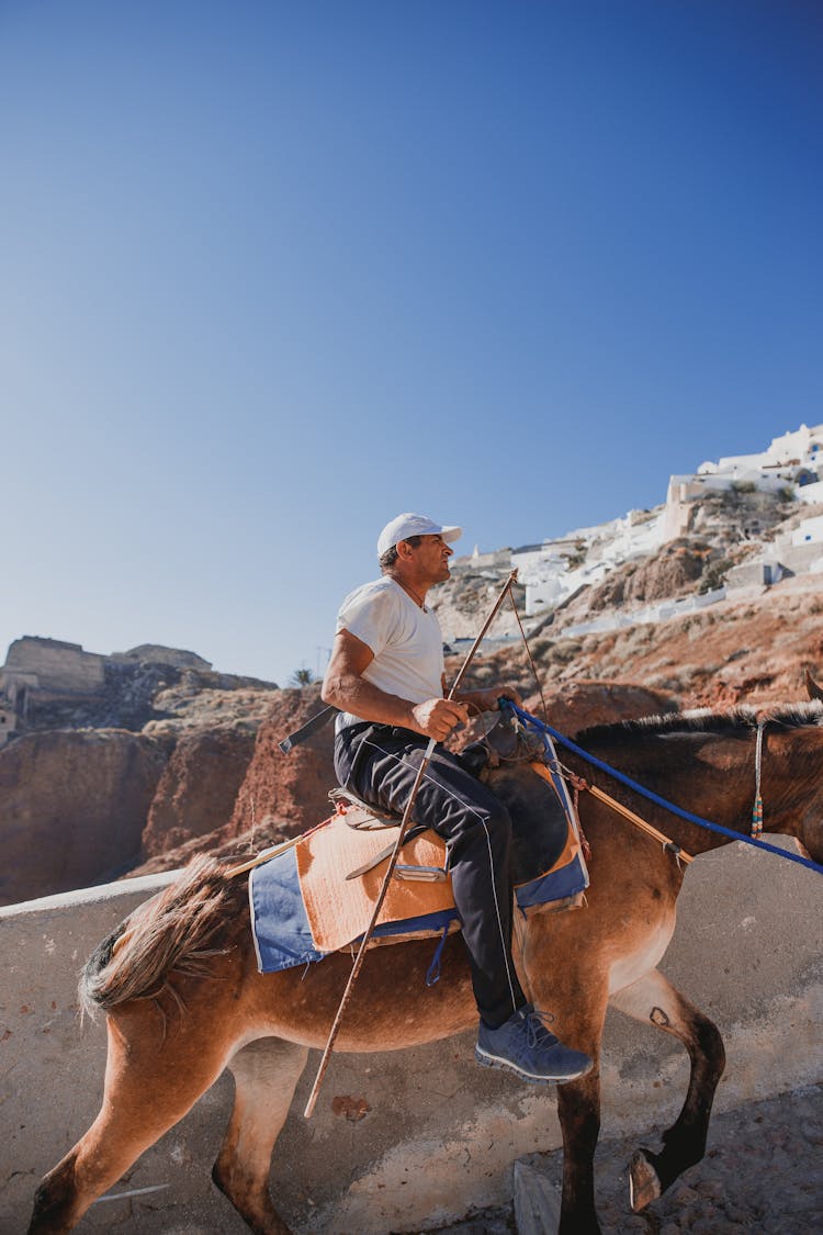 Young Man Riding Horse In Rocky Terrain On Sunny Day