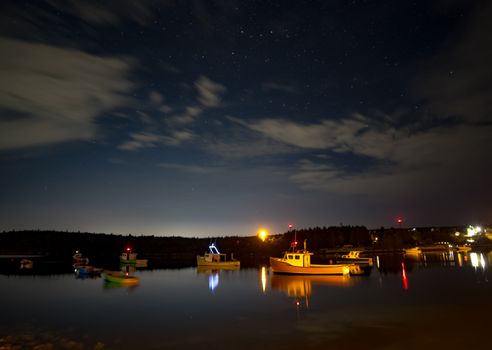 在布满星星的天空下，一艘船的宁静夜景照亮了平静的加拿大湖面