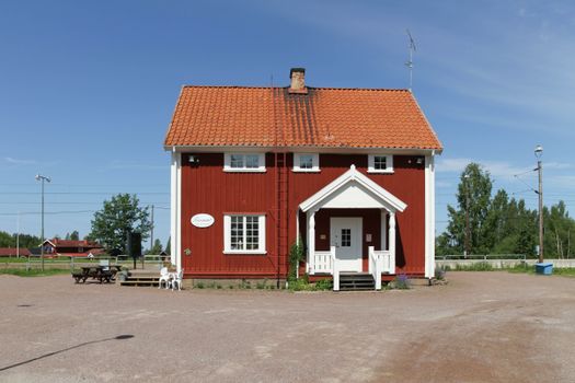 Red and White Wooden House Near Green Trees Under Blue Sky
