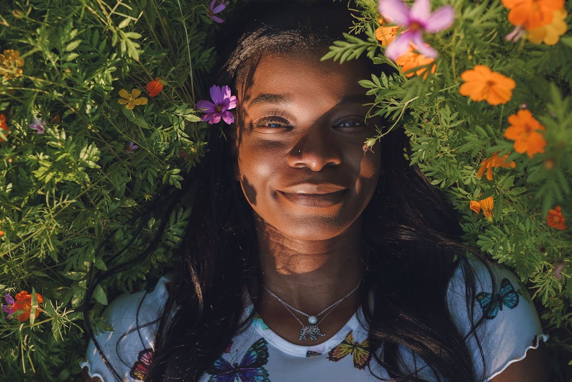Happy black woman lying on grass with flowers