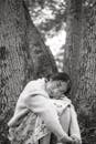 Calm Asian woman hugging knees while resting in woods