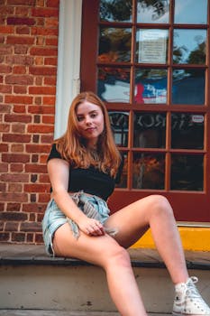 Young woman in casual attire sitting on steps in urban setting.