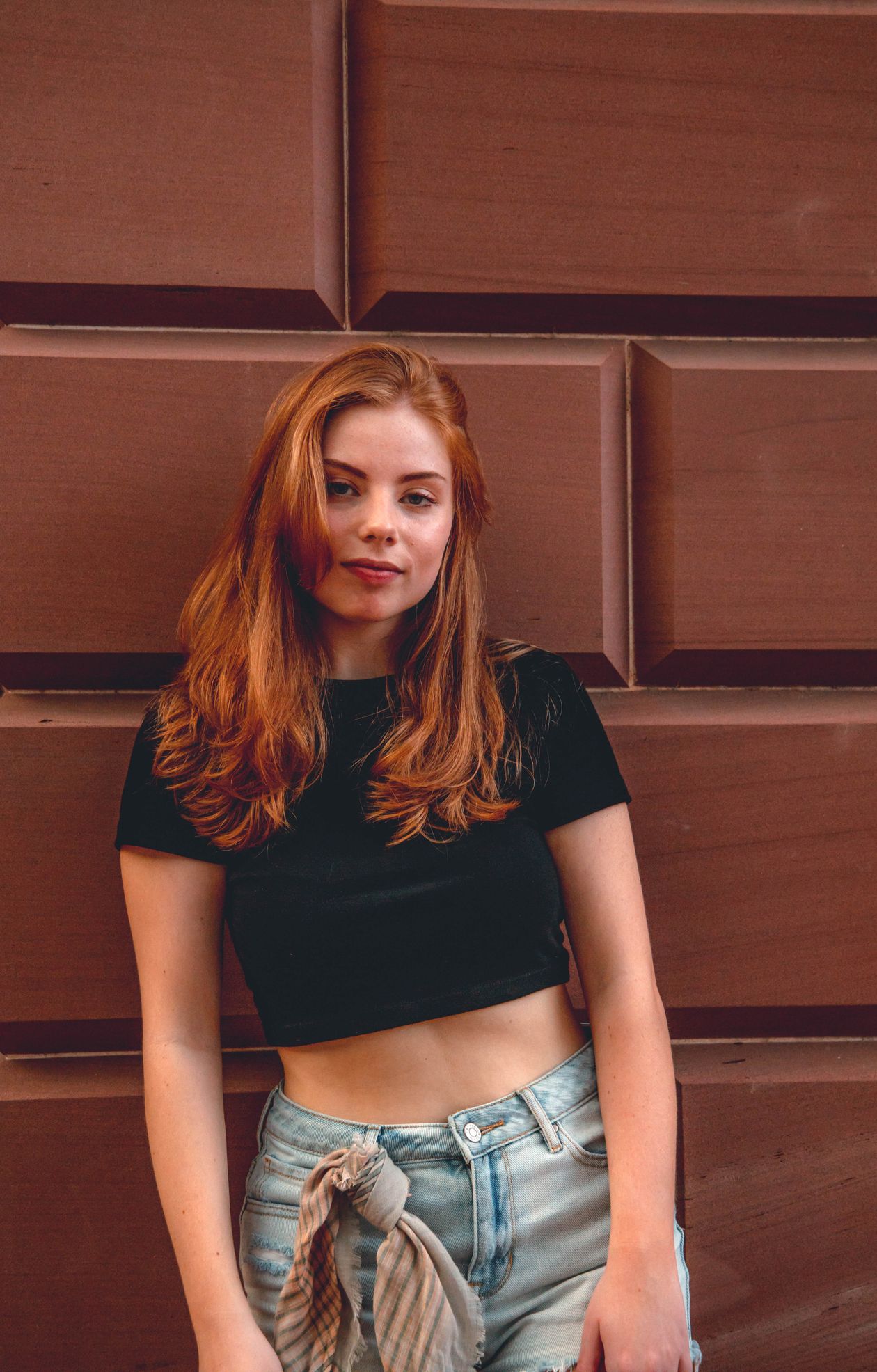 Woman in a black crop top and jeans with a shirt tied at the waist