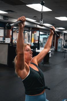 Woman working out on exercise machine in a gym environment, showcasing strength and fitness.