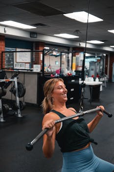 A woman enjoying a workout using a cable machine in a modern gym.