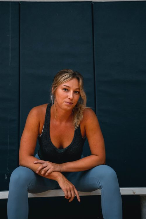 Free A confident woman sits on a bench indoors, radiating strength and poise. Ideal for lifestyle themes. Stock Photo