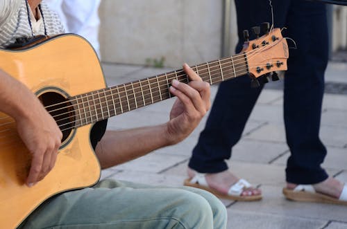 Gratis Orang Dengan Kemeja Abu Abu Dan Jeans Denim Biru, Bermain Gitar Akustik Foto Stok