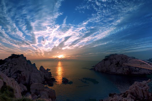 Beautiful sunrise over the ocean with dramatic clouds and rocky seascape.