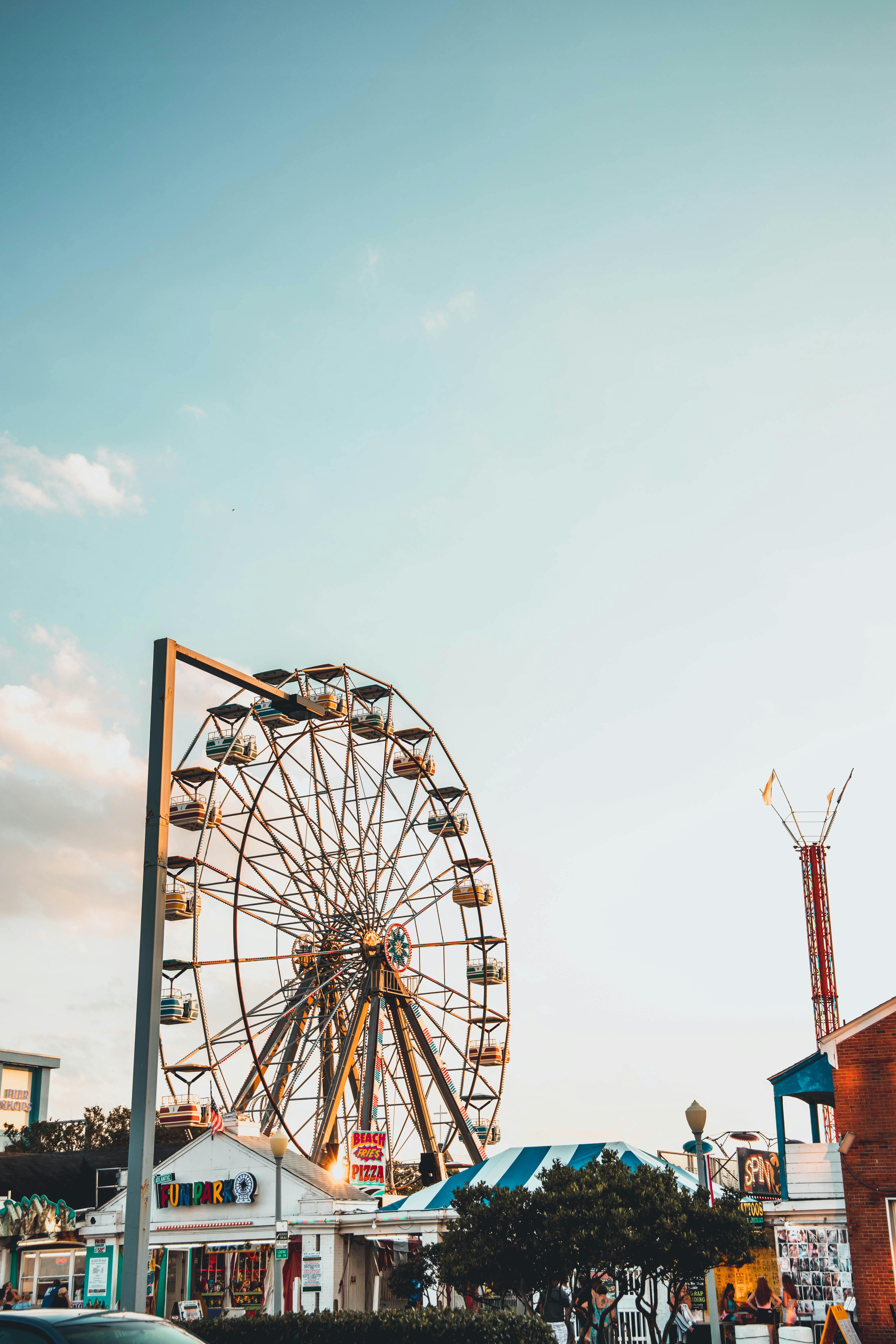 Bright and cheerful scene of a Ferris wheel at an amusement park, under a clear sky.