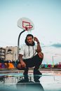 Man Kneeling by Puddle on Basketball Cou