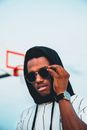 Young Man in Hood and Sunglasses against Blue Sky