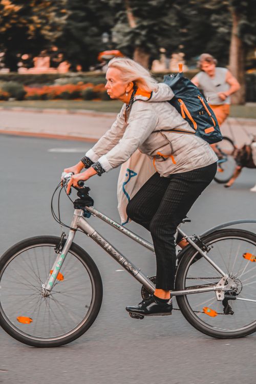 Free Elderly woman commuting on a bicycle in an urban setting, showcasing active lifestyle and fitness. Stock Photo
