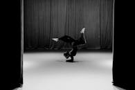 一名舞者在空舞台上，对着窗帘表演动态倒立