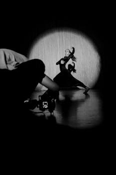 Elegant dancer captured in a moody, monochrome spotlight on stage.
