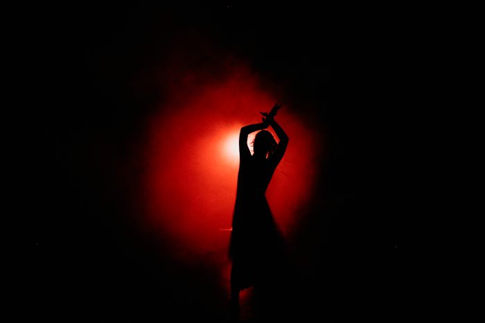 Dancer silhouetted against a glowing red stage light