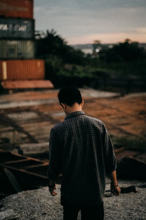 Free Silhouette of a man standing outdoors with a blurred industrial background. Stock Photo