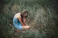 Pensive anonymous woman sitting on grass