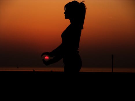 Force Perspective Photography of a Silhouette of a Woman Holding the Sun