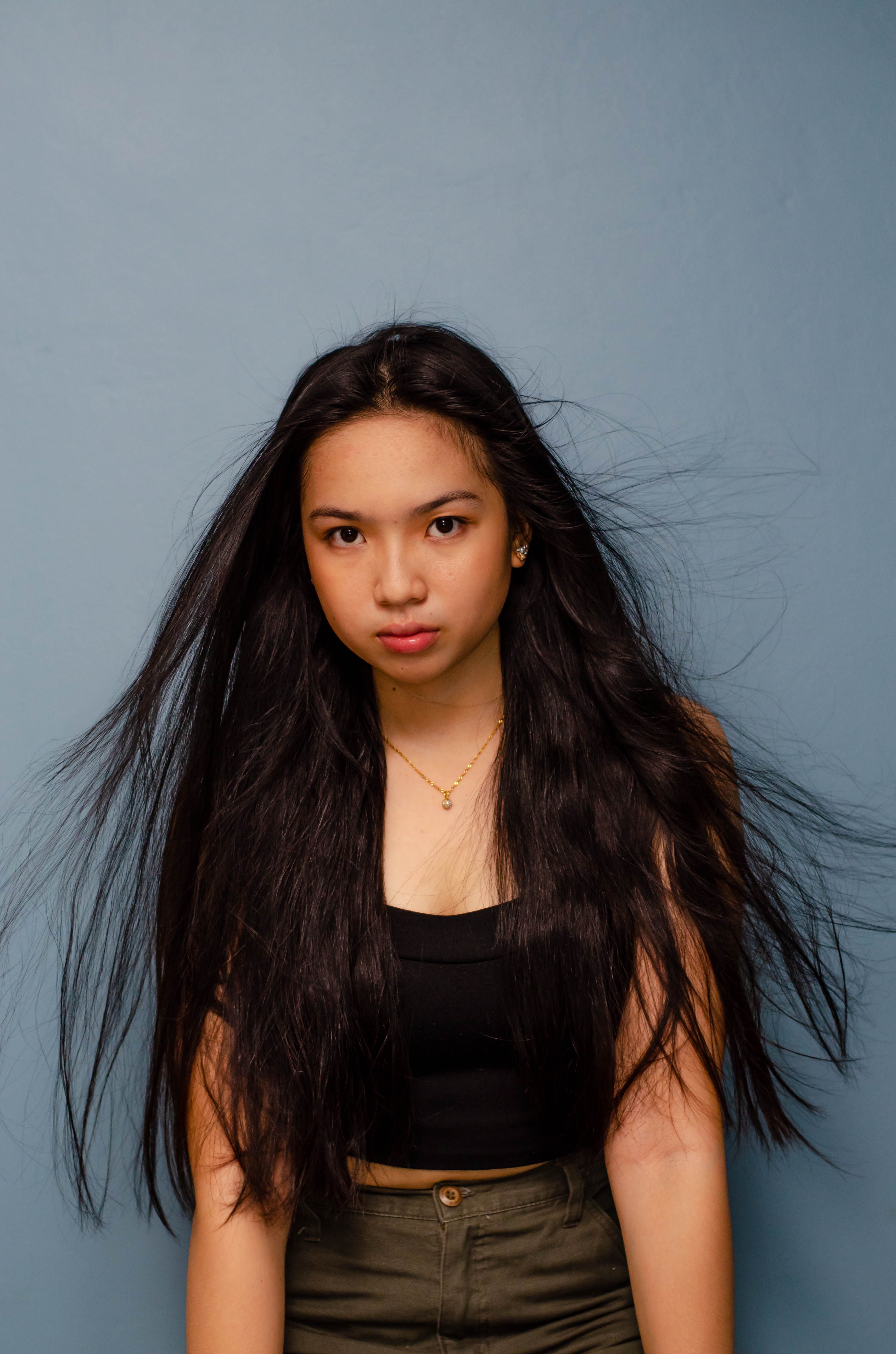 A portrait of a young woman with long flowing hair in a studio setting, wearing a black top.