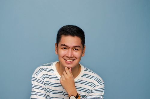 Free Millennial man smiling confidently in a studio with a blue background. Stock Photo
