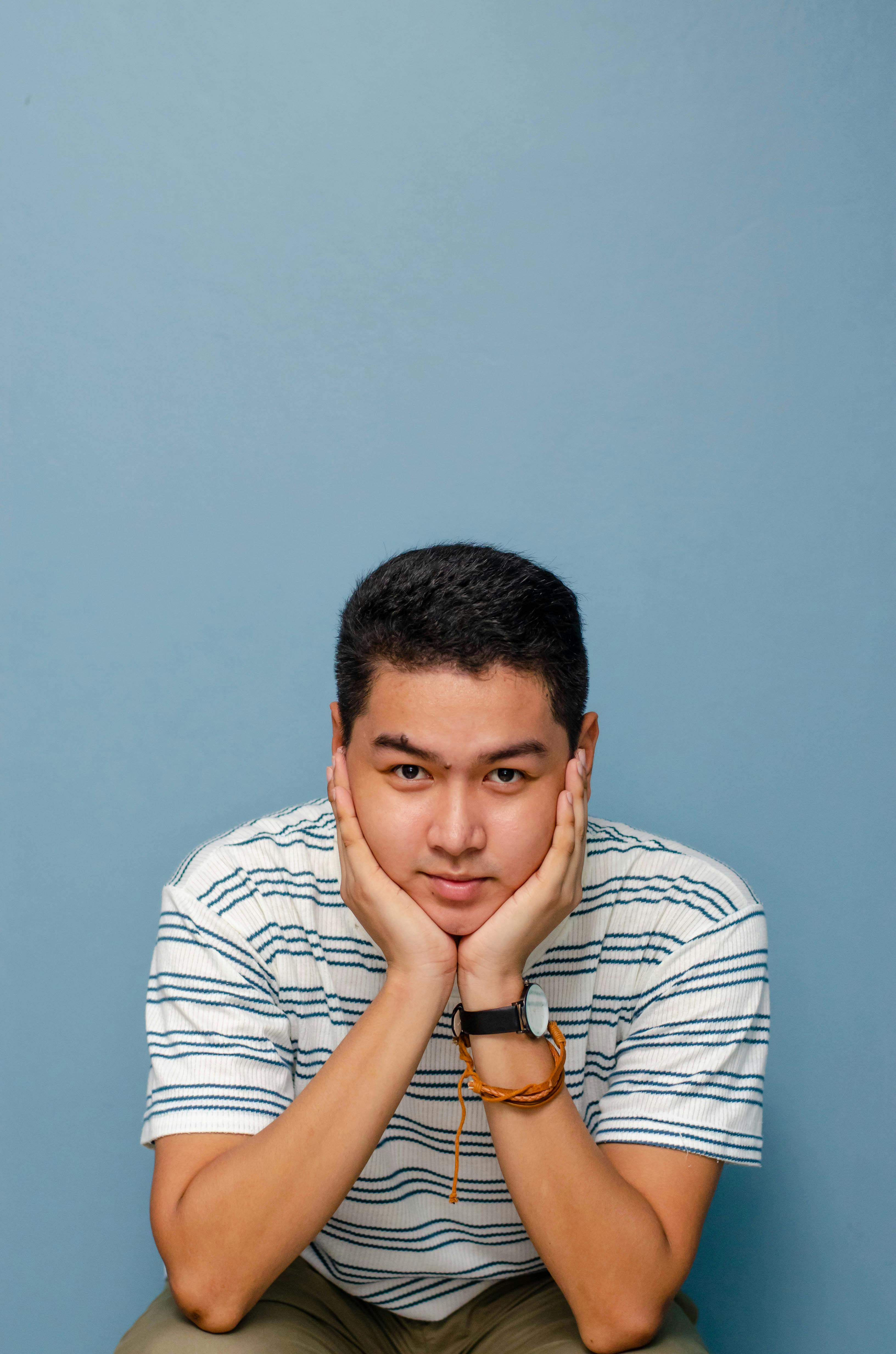 man wearing striped shirt with hands on face