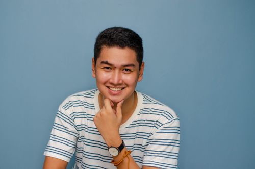 Free Studio portrait of a smiling man in a striped shirt with a blue background. Stock Photo