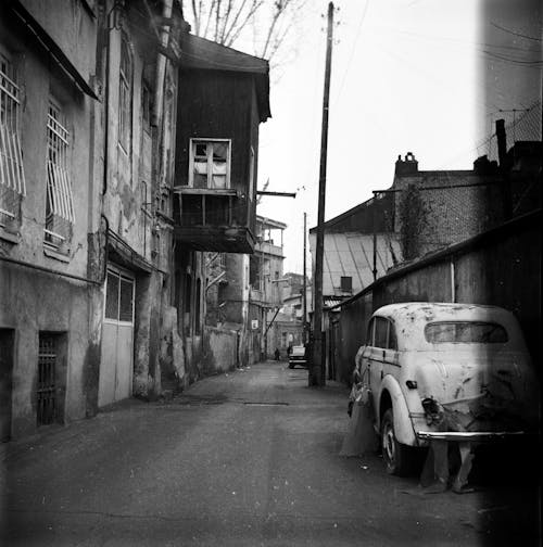 Foto Grayscale Mobil yang Diparkir Di Samping Gedung