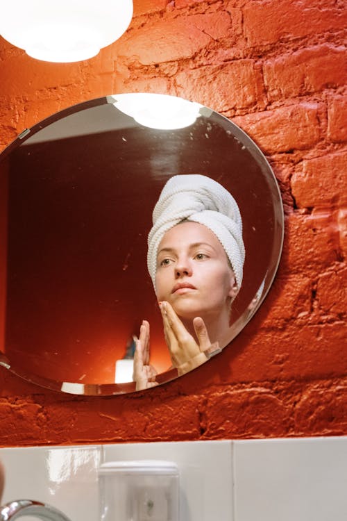 Woman Looking In The Mirror With Hands On Face