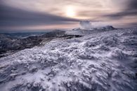 在宁静的日出天空下，白雪皑皑的山脉令人惊叹，尽显冬季之美