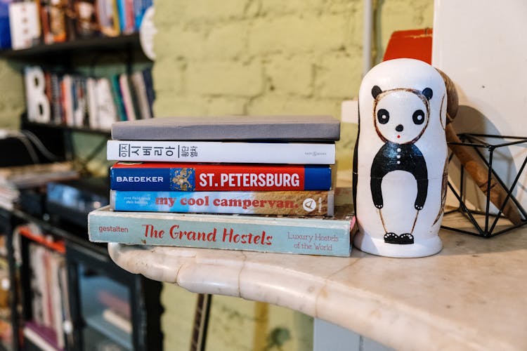 Stack Of Books Beside A Ceramic Decoration On Marble Top Table