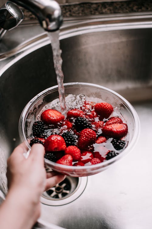 Person Washing Fruits in a Bowl