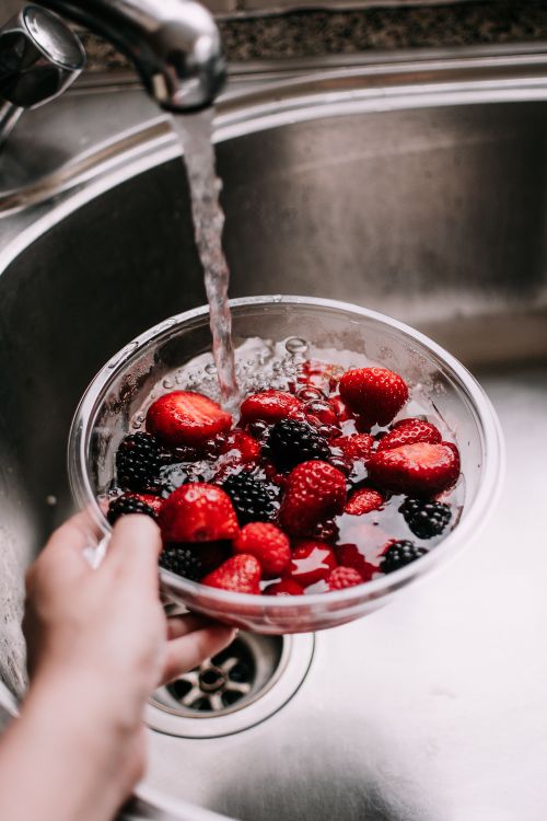 Free Close-up of fresh strawberries and blackberries being washed in a kitchen sink. Stock Photo