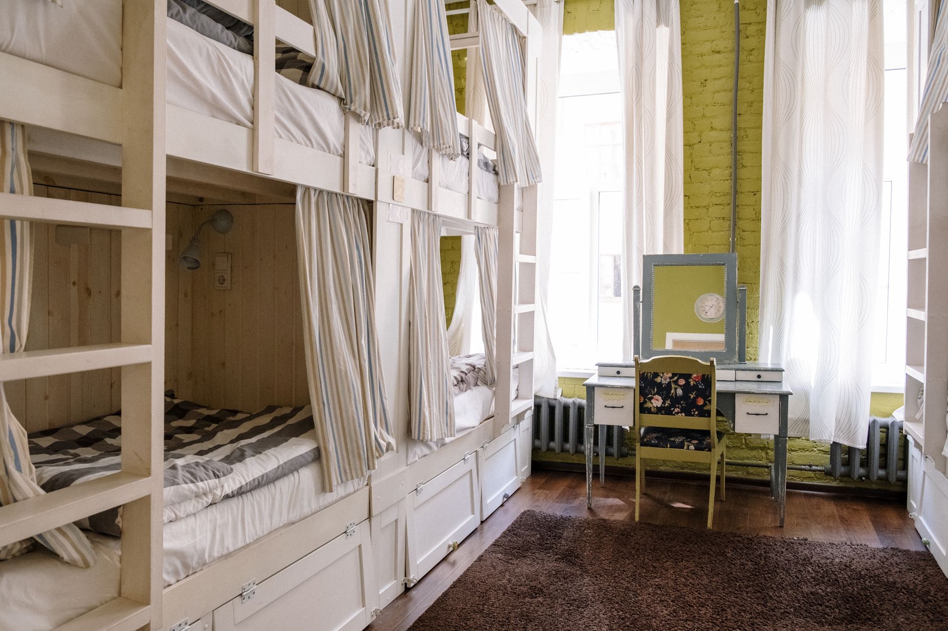Student vacuuming the carpet in a bright bedroom next to a wooden desk