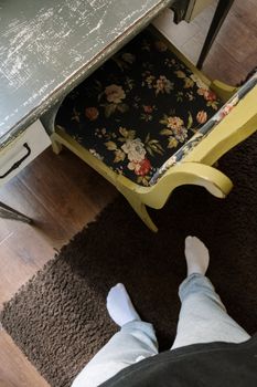 一张航拍照片中，人站在棕色地毯上，旁边是花卉图案椅子和复古办公桌