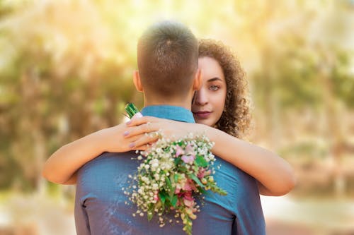 Woman Hugging a Man and Holding a Bouquet 