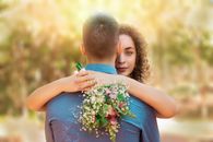 Woman Hugging a Man and Holding a Bouquet