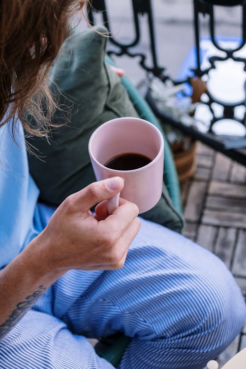 A Person in Blue Shirt Holding a Ceramic Mug