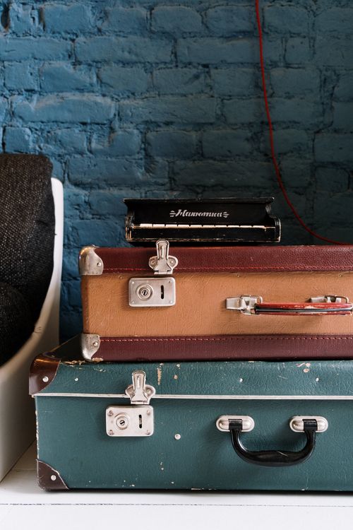 Free Stack of vintage suitcases against a rustic blue brick wall, ideal for travel themes. Stock Photo